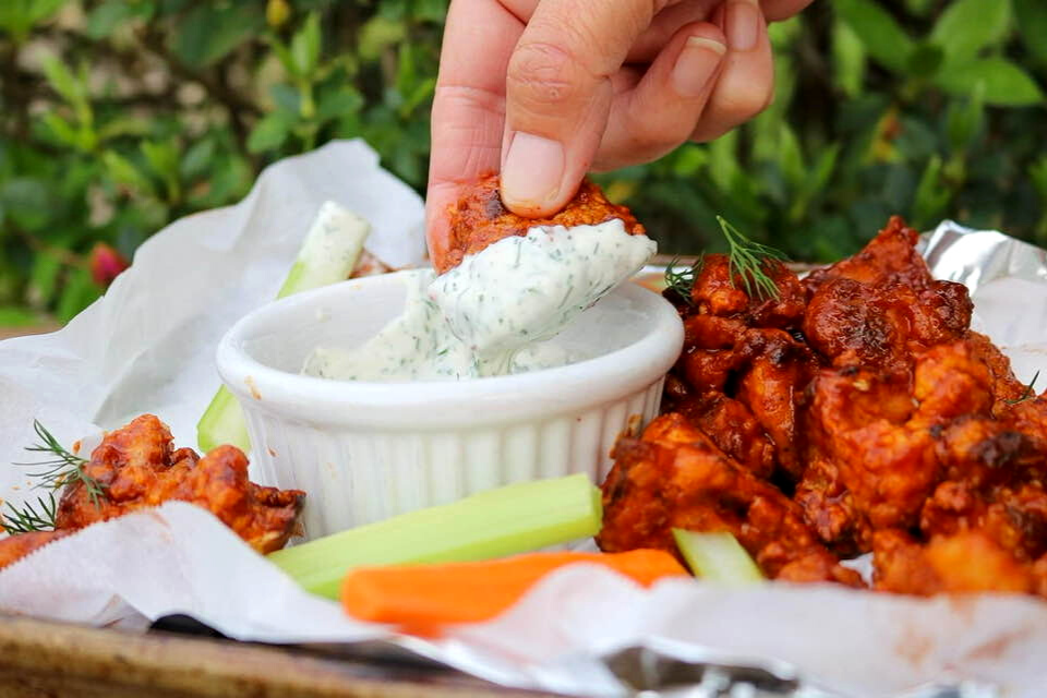 Dipping a cauliflower wing into vegan ranch